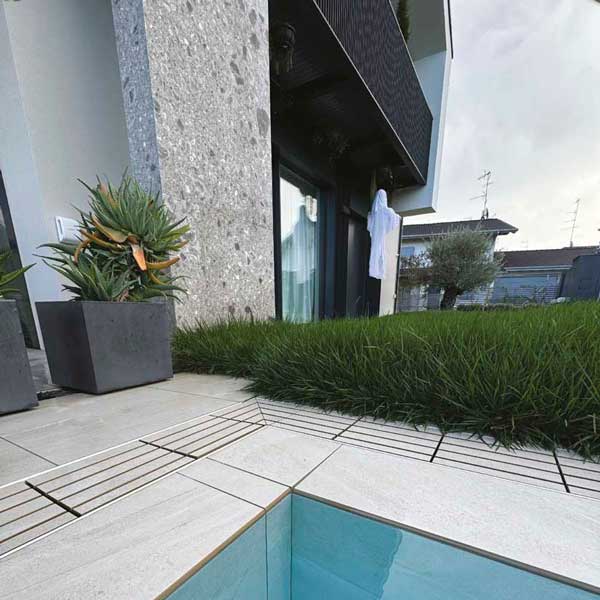 piscina a sfioro con griglia e pavimento ceppo di grè