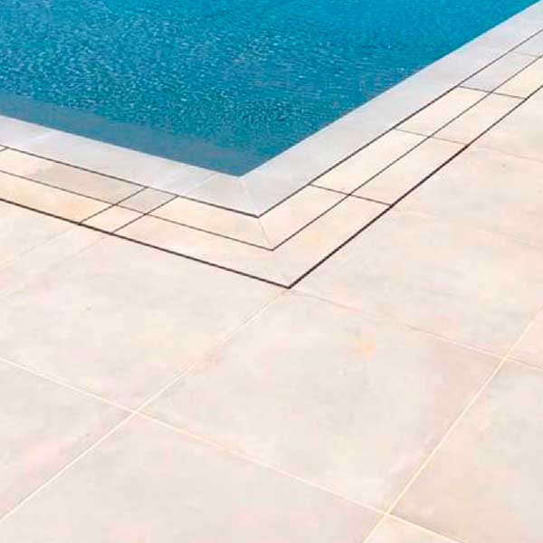 Piscina a sfioro con pavimento e griglia directa effetto cemento minimal beige
