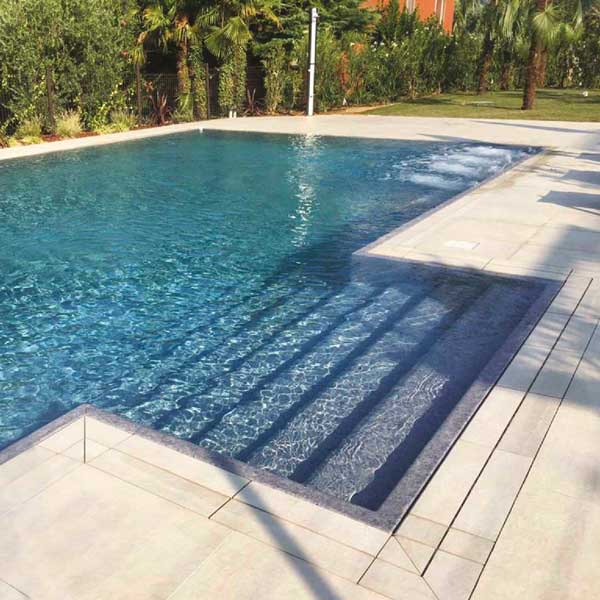 Piscina a sfioro con pavimento e griglia directa effetto cemento minimal beige