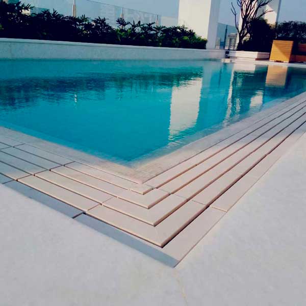 Piscina a sfioro con pavimento e griglia directa effetto cemento minimal white
