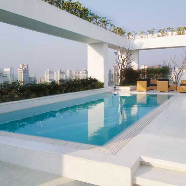 Piscina a sfioro con pavimento e griglia directa effetto cemento minimal white