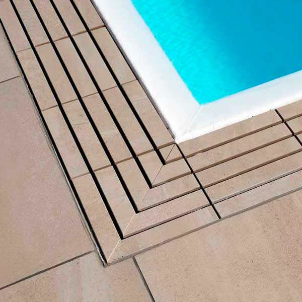 Piscina a sfioro con pavimento e griglia directa effetto pietra meta beige