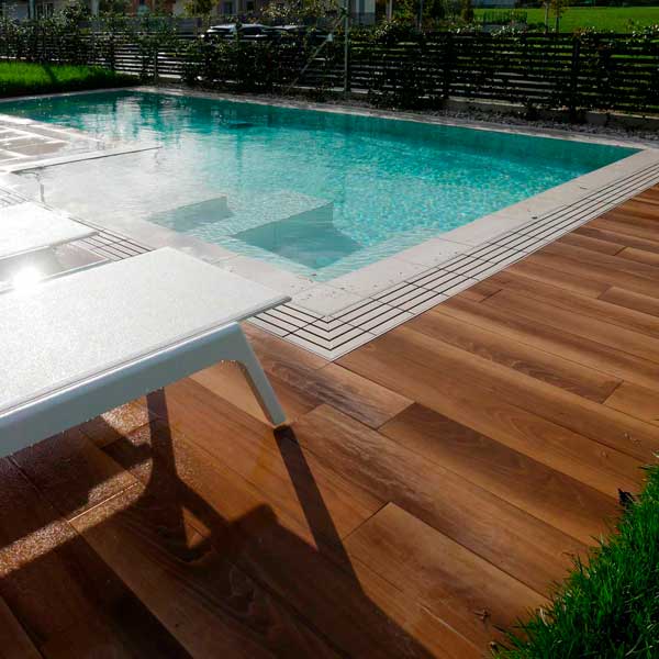 Piscina a sfioro con pavimento wood teak e griglia directa effetto pietra meta white