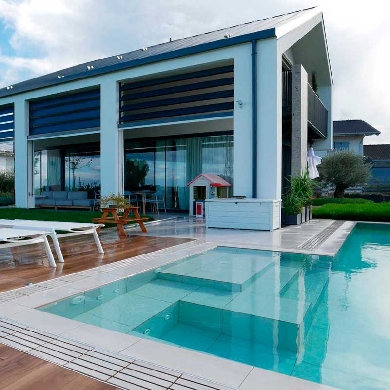 Piscina a sfioro con pavimento wood teak e griglia directa effetto pietra meta white