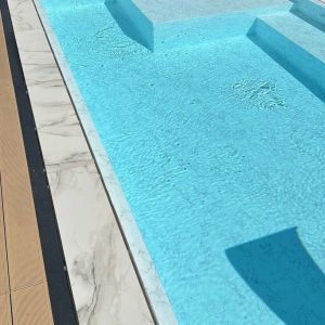 Immagine di bordo piscina con pavimento in gres per piscine a sfioro effetto marmo Calacatta - dettaglio bordo