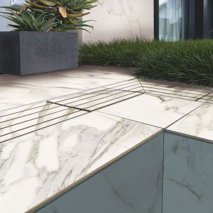 Immagine di bordo piscina con pavimento in gres per piscine a sfioro effetto marmo Calacatta - dettaglio angolo