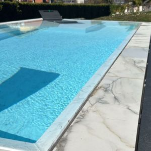Immagine di bordo piscina con pavimento in gres per piscine a sfioro effetto marmo Calacatta - dettaglio angolo